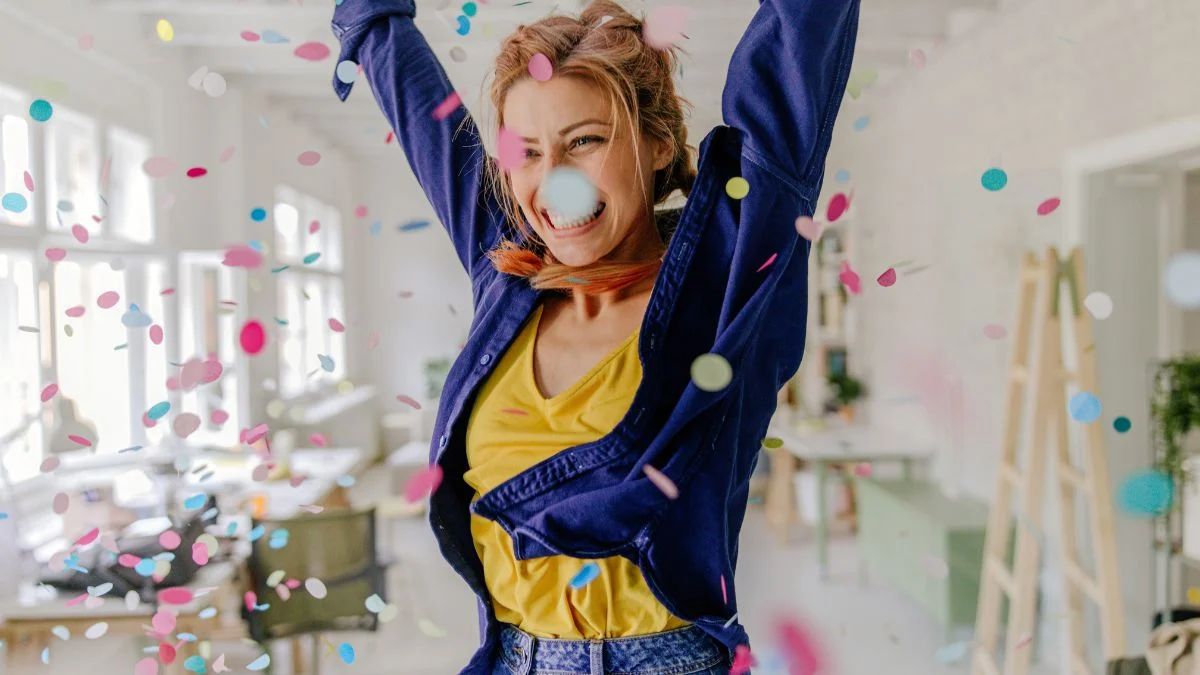 a woman celebrating in an office with confetti