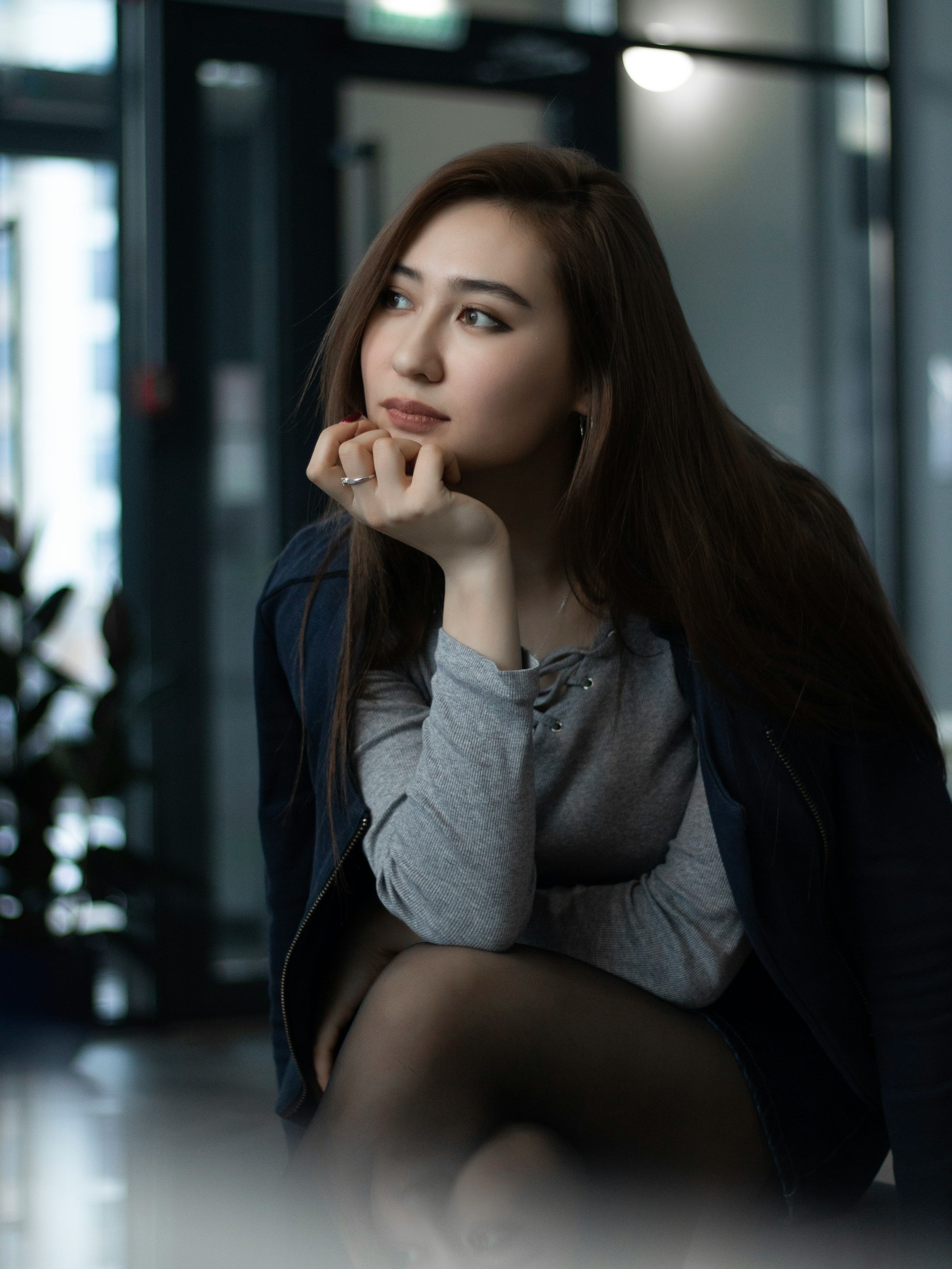 a woman sitting on the ground with her hand on her chin